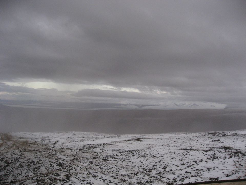 Snowy landscape with dark clouds and distant mountains