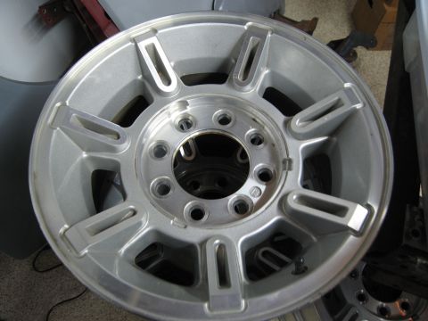 1986 Ford Bronco - A single aluminum wheel is shown, with other wheels stacked behind it in the background.