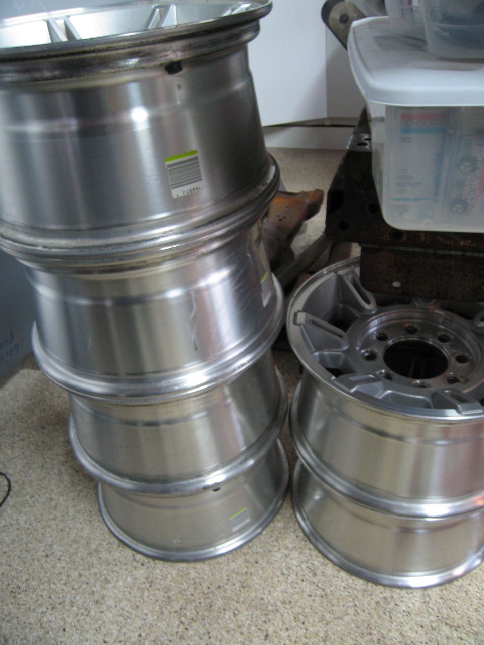 Stack of four aluminum wheels with a fifth wheel on top, and another stack of two wheels to the right