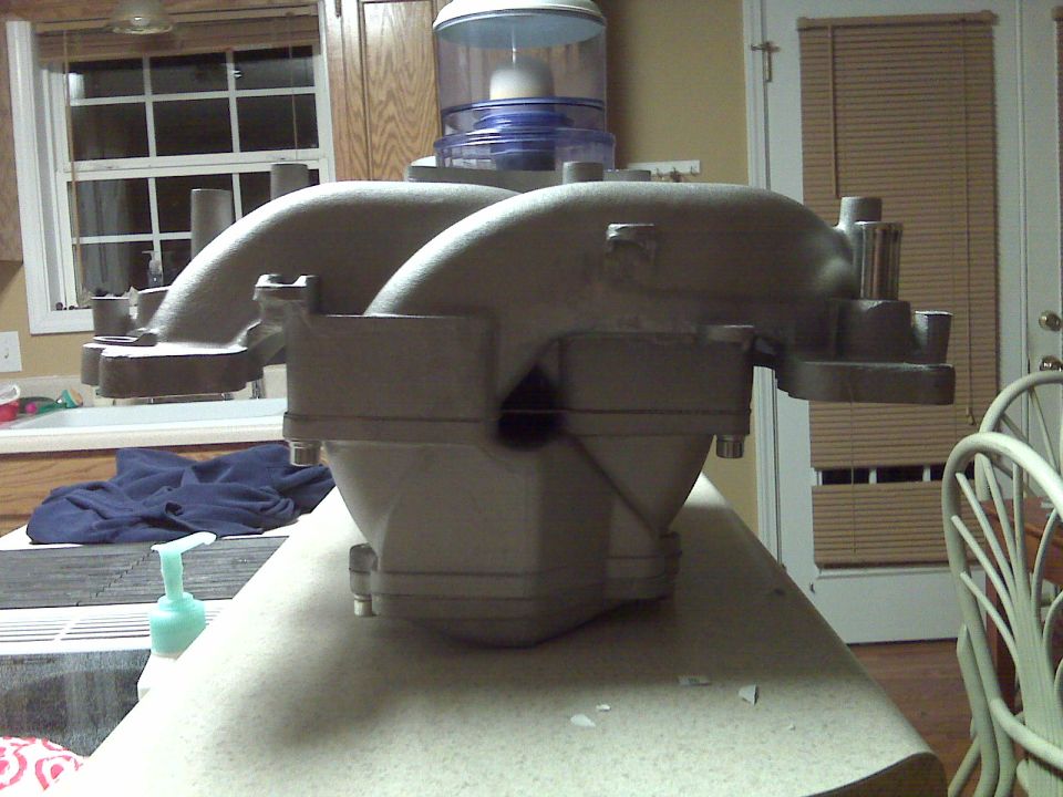 Engine intake manifold on a countertop, with kitchen background. Water cooler visible