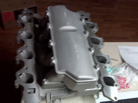 2001 Ford Crown Victoria - A silver intake manifold is shown from a top-down perspective on a wooden surface.