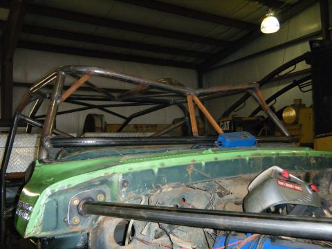 1978 Ford Bronco - A custom roll cage is installed on a green vehicle, with the engine bay visible and metal fabrication evident.