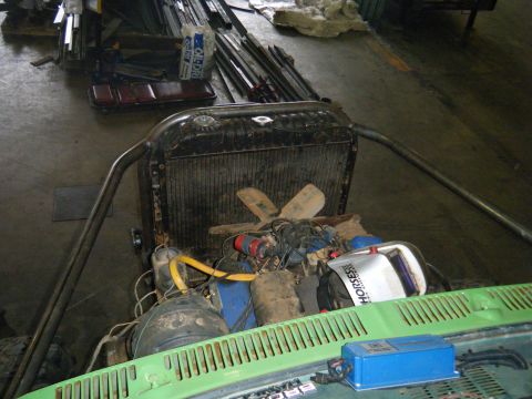 1978 Ford Bronco - The engine bay of a vehicle is shown, the radiator, fan, and engine parts, with roll cage elements.