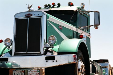 1981 Kenworth W900A - A green Peterbilt truck is shown from a three-quarter front view against a clear blue sky.