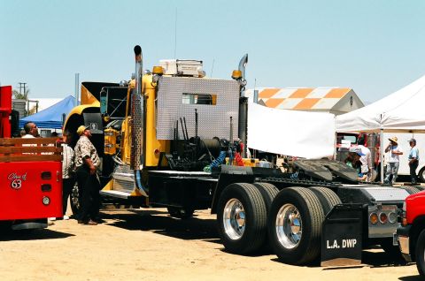 1981 Kenworth W900A - A yellow 1981 Kenworth W900A semi-truck is parked outdoors with people around it.