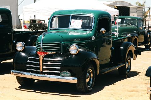 1981 Kenworth W900A - A classic green Dodge pickup truck is parked outdoors, with another similar truck visible behind it.