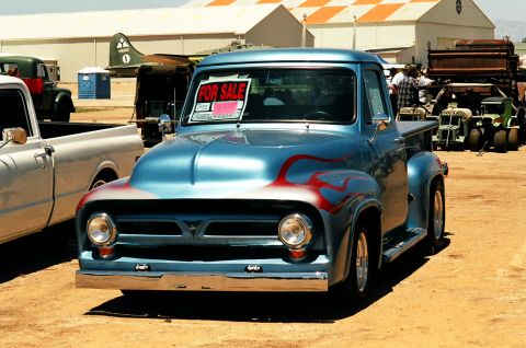 1981 Kenworth W900A - A blue 1955 Ford F-100 pickup truck with flame graphics is for sale at an outdoor event.