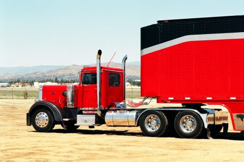 1981 Kenworth W900A - A red 1981 Kenworth W900A semi-truck is parked in a dirt lot under a clear blue sky.