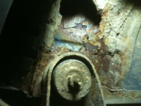 1993 Ford Bronco - Close-up view of severe rust and corrosion on a vehicle's undercarriage component.