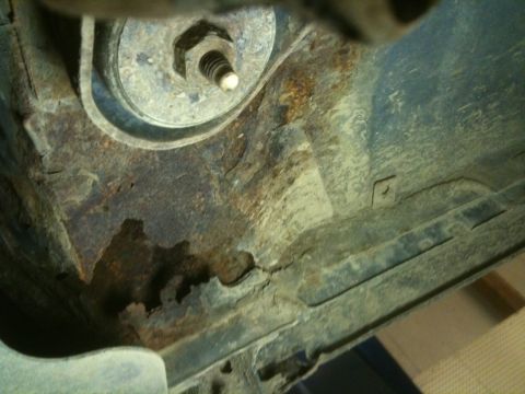 1993 Ford Bronco - Close-up view of a heavily rusted vehicle frame section, showing a bolt and washer.