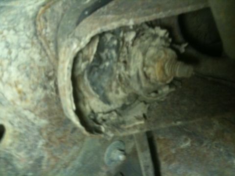 1993 Ford Bronco - Close-up of a heavily rusted suspension component, likely from the undercarriage of a vehicle.