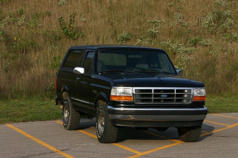 Black two-door Ford Bronco SUV parked on lot near grassy field