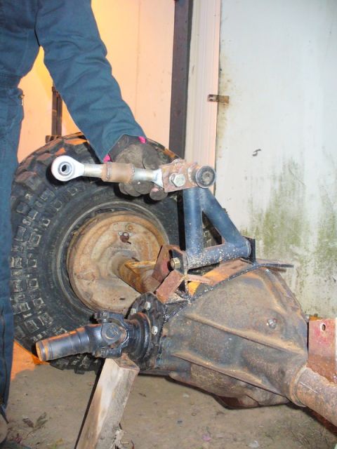 1994 Ford Bronco - A person's hand holds a linkage attached to a vehicle axle assembly with a tire.