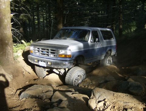 1996 Ford Bronco - Ford Bronco tackling a challenging rocky trail in a wooded area.