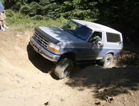 1996 Ford Bronco - A 1996 Ford Bronco navigates a challenging dirt path, kicking up dust as it goes.