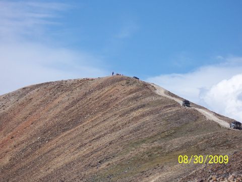 1994 Ford Bronco - Multiple off-road vehicles ascend a mountain trail on a clear day.