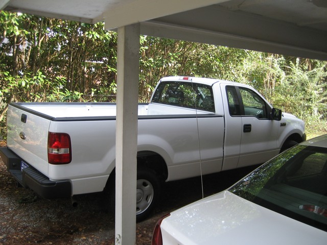 Side view of a white 2004 Ford F-150 pickup truck parked under a carport