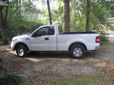2004 Ford F-150 - White 2004 Ford F-150 pickup truck parked on a wooded lot.