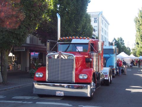 1981 Kenworth W900A - A classic red 1981 Kenworth W900A semi-truck is parked on a street, with another truck visible behind it.