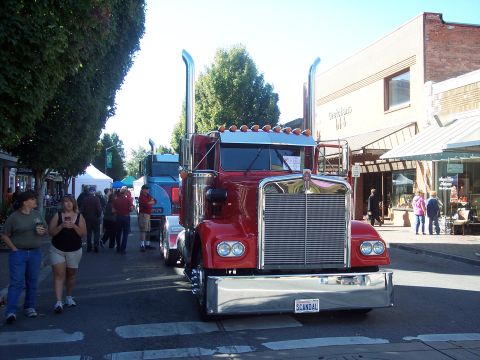 1981 Kenworth W900A - A red 1981 Kenworth W900A semi-truck is parked on a street, with other vehicles and pedestrians visible.