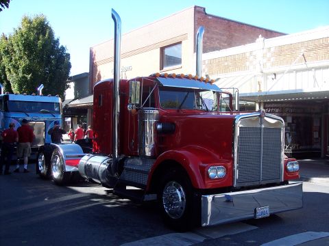 1981 Kenworth W900A - A red 1981 Kenworth W900A semi-truck is parked on a street, with another truck visible behind it.