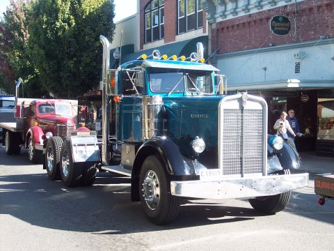 1981 Kenworth W900A - A teal Kenworth truck is seen from the front-right, with another vintage truck behind it.