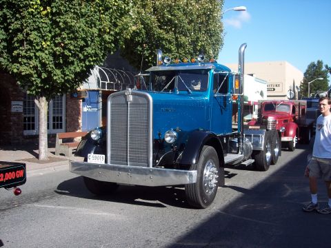 1981 Kenworth W900A - A blue Kenworth semi-truck is parked on a street, with another truck visible behind it.
