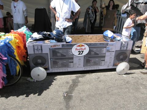 1986 Ford Bronco - A soapbox derby car designed to look like a boombox is seen at an event.
