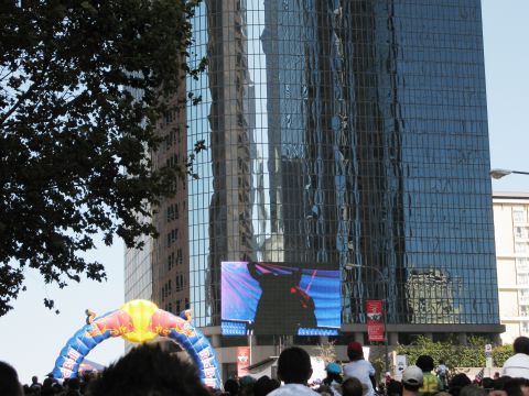 1986 Ford Bronco - Crowd gathered under a Red Bull arch in front of a modern building with a large display screen.