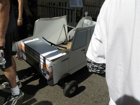 1986 Ford Bronco - A homemade soapbox car resembling a Bronco, built from cardboard and other materials, is displayed at an event.