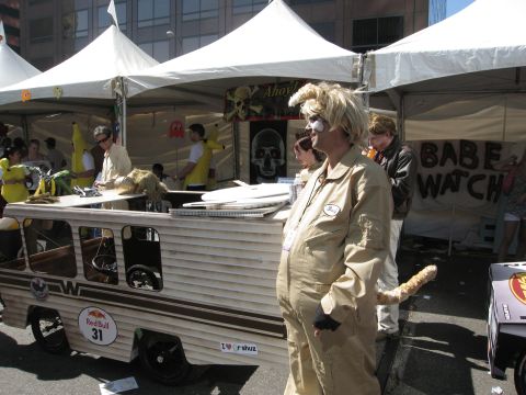 1986 Ford Bronco - A custom-built vehicle is displayed at an outdoor event, with attendees in costumes and promotional banners in the background.