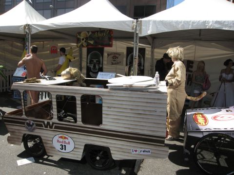 1986 Ford Bronco - A custom-built vehicle, possibly a soapbox derby entry, is displayed under tents with people around.