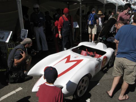 1986 Ford Bronco - A white soap box derby car with red M emblem is displayed at an outdoor event.