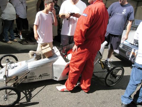 1986 Ford Bronco - A custom-built soap box derby car is examined by onlookers at an event.