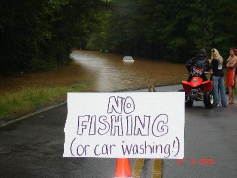 1979 Ford F-150 - A flooded road scene with a submerged car, an ATV, and onlookers gathered near a sign.