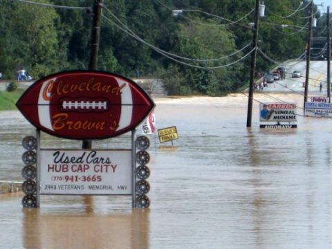 1979 Ford F-150 - Flooding inundates a street, submerging business signs and surrounding areas.