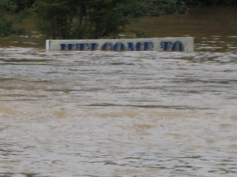 1979 Ford F-150 - A sign is submerged in floodwaters, with trees visible in the background.