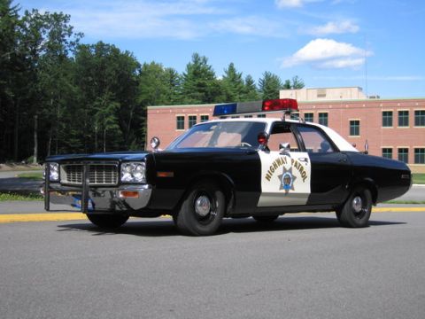 2001 Ford Crown Victoria - This police car, likely a 1977 model, is seen from a three-quarter front angle in front of a brick building.