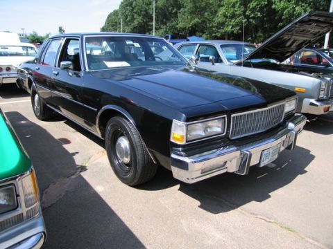 2001 Ford Crown Victoria - This black sedan has a distinctive grille and chrome accents, parked outdoors.