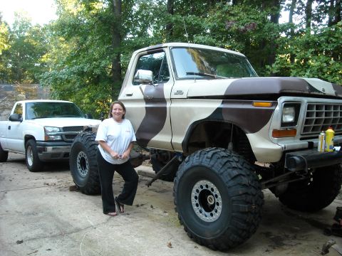 1979 Ford F-150 - A woman poses with a heavily modified 1979 Ford F-150 a camouflage paint scheme and oversized tires.