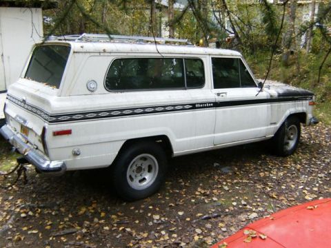 2000 Ford E350 - This Jeep Grand Wagoneer is parked on a dirt lot with fallen leaves scattered around.