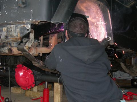 1991 Jeep Wrangler - A person is welding the frame of a vehicle, with sparks flying from the work.