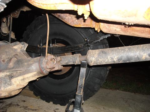 1979 Ford F-150 - Close-up view of the rear axle, leaf springs, and driveshaft of a truck, with a jack stand providing support.