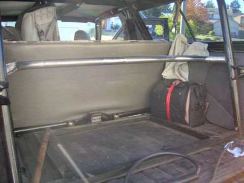 1996 Ford Bronco - The interior of a vehicle shows a roll cage and a duffel bag secured with straps.