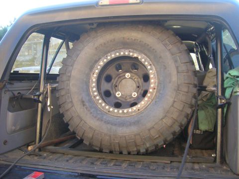 1996 Ford Bronco - Spare tire with a beadlock wheel is mounted inside the cargo area of a vehicle, obscuring the interior.