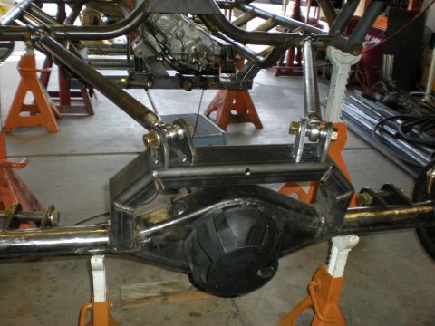 Suzuki Samurai - Close-up rear view of a custom tube-frame chassis showing a black-painted solid rear axle housing suspended by bare-metal trailing arms and…