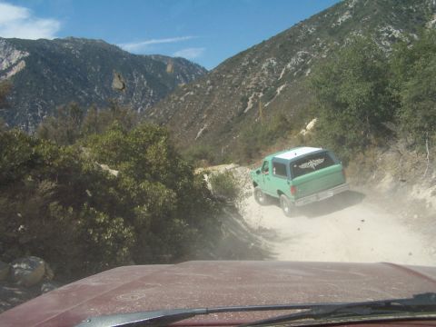 1990 Ford Bronco - Green 1990 Ford Bronco navigates a dusty trail in the mountains.