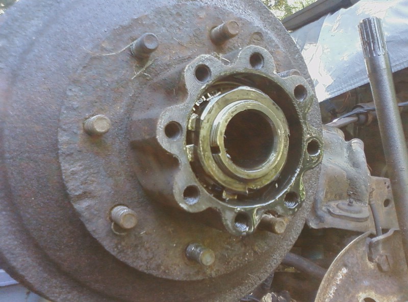 Rusty wheel hub assembly with visible bearing and lug studs