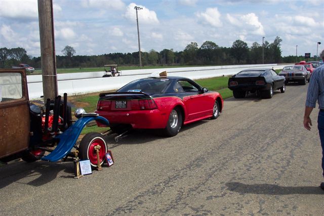 Red and black Ford Mustang with custom plate, viewed from rear