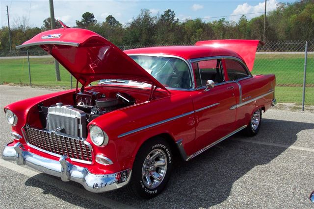 Red 1955 Chevrolet sedan with hood and trunk open, showing the engine